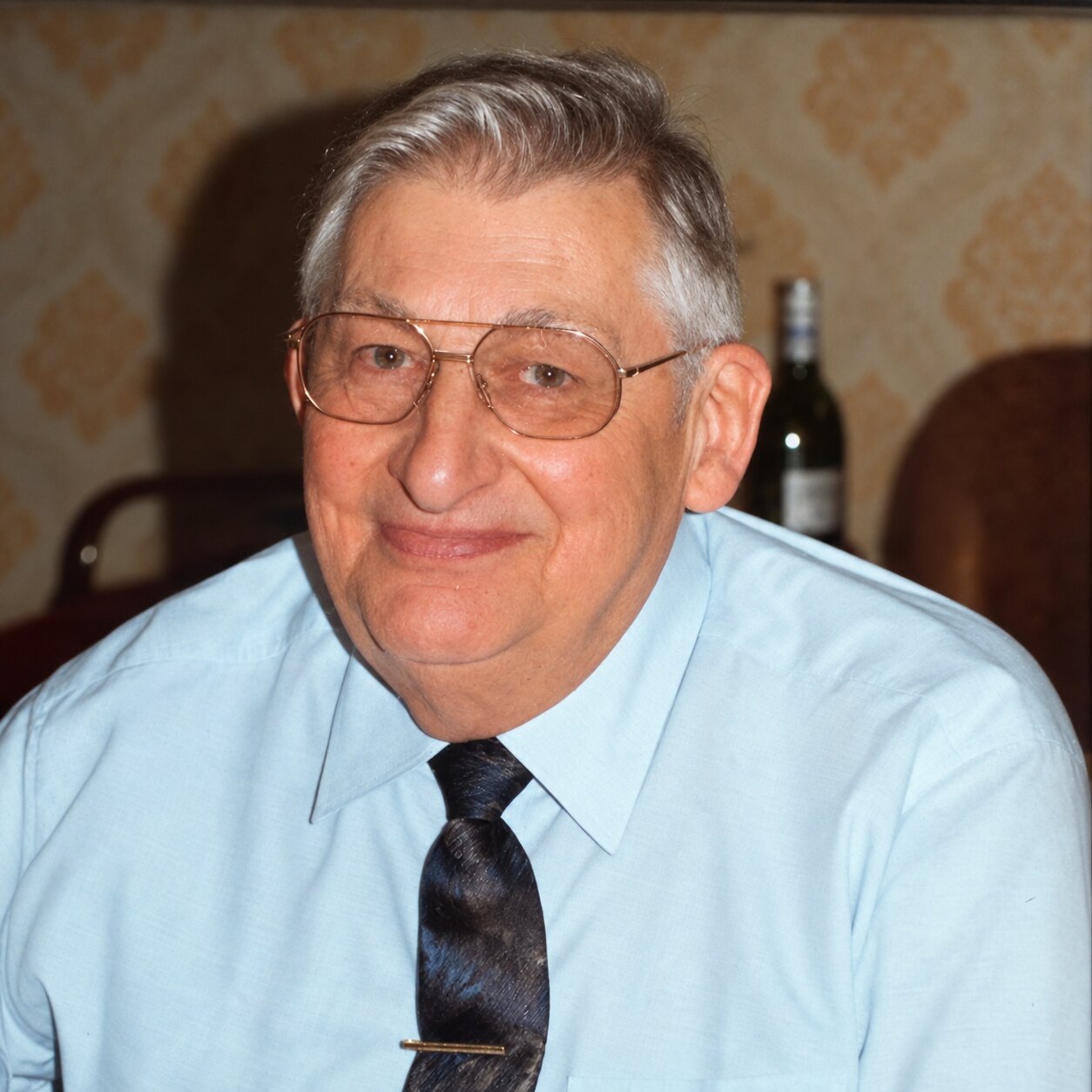 Antoine, souriant, en chemise bleue et cravate