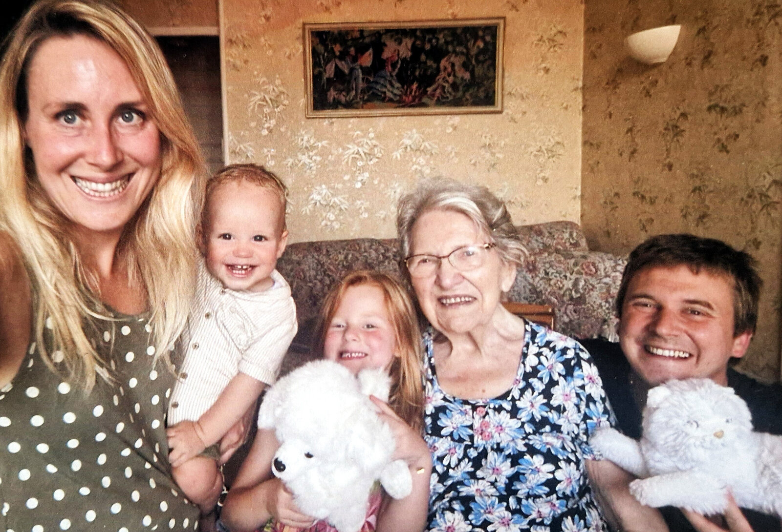 Yvonne sur son canapé, entourée de deux adultes et de deux jeunes enfants avec leurs peluches
